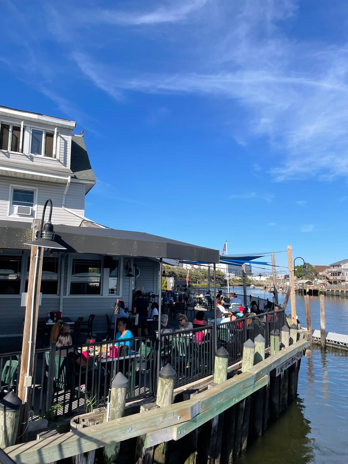Bayhouse's outdoor deck over the water, full of diners on a sunny afternoon